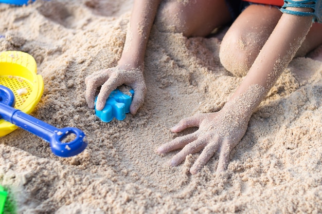 close-up criança mão jogando brinquedo na praia de areia