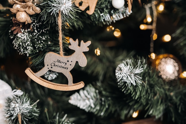 Close-up da árvore de Natal com um veado pendurado e a inscrição feliz Natal.