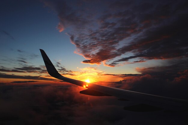 Foto close-up da asa do avião contra o céu durante o pôr do sol