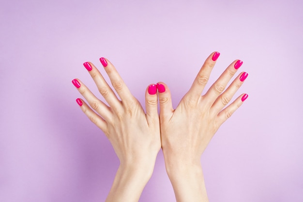 Close-up da bela manicure. lindas mãos de uma jovem em um plano de fundo roxo leigos.