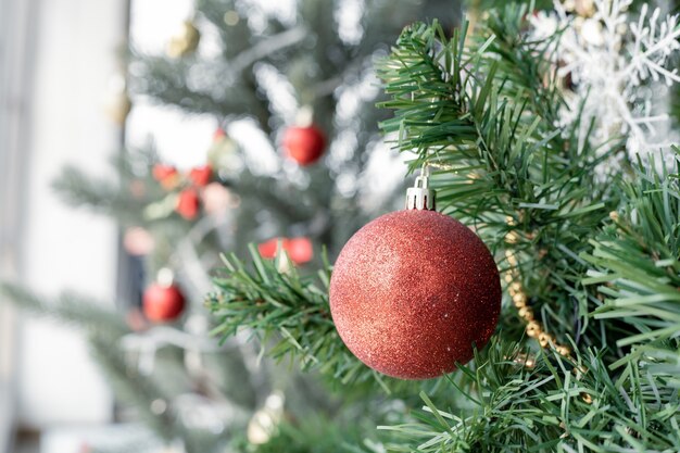Close-up da bola vermelha pendurada em uma árvore de Natal decorada com espaço de cópia. Fundo de férias de Natal e ano novo.