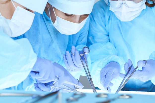 Close-up da equipe médica realizando a operação. Grupo de cirurgiões no trabalho estão ocupados com o paciente. Medicina, veterinária ou saúde e emergência no hospital.