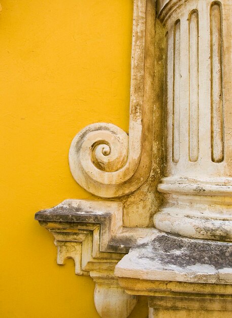 Close-up da estátua contra a parede amarela