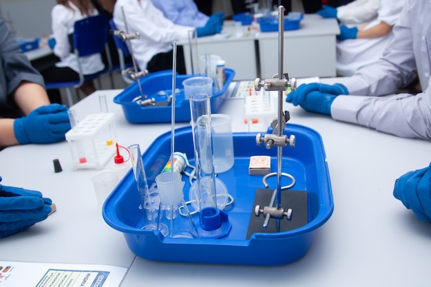 Close-up da experiência química. Mãos enluvadas seguram um frasco com líquido. Experimentos escolares. Aulas de química. Laboratório. Foto de alta qualidade