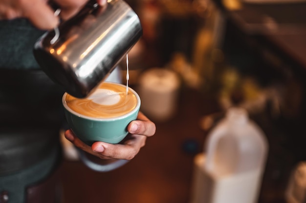 Close-up da extração profissional do café do barista com um derramamento de leite fervido em uma xícara de café, fazendo uma bela latte art. café, extração, profundo, xícara, arte, conceito de barista.