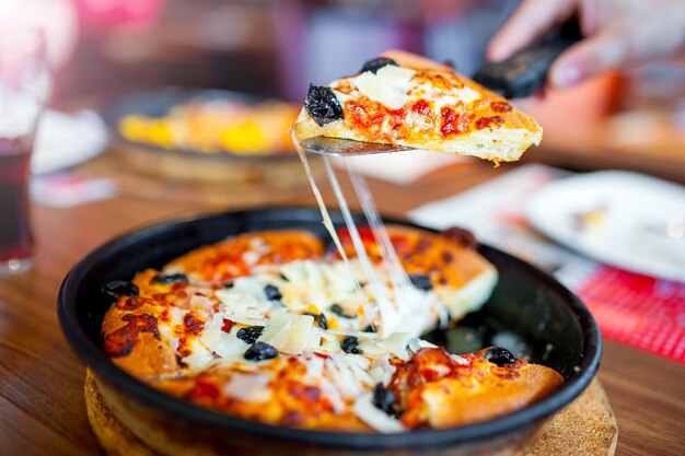 Foto close up da fatia levantada da pizza fresca quente com ingredientes frescos