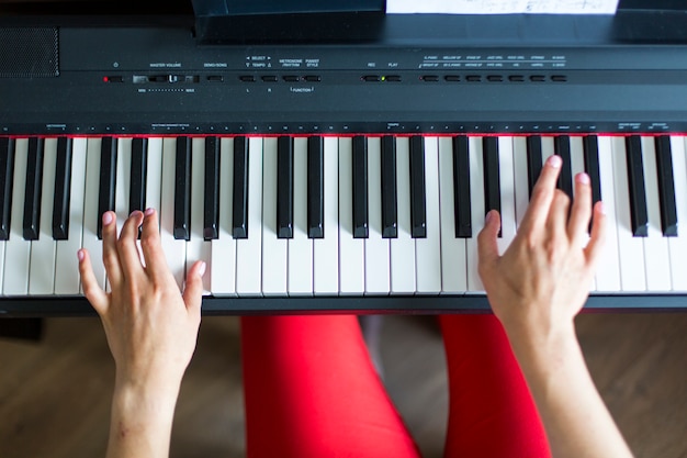 Close-up da garota de mão de um artista de música clássica tocando piano ou sintetizador eletrônico (teclado de piano) tiro superior