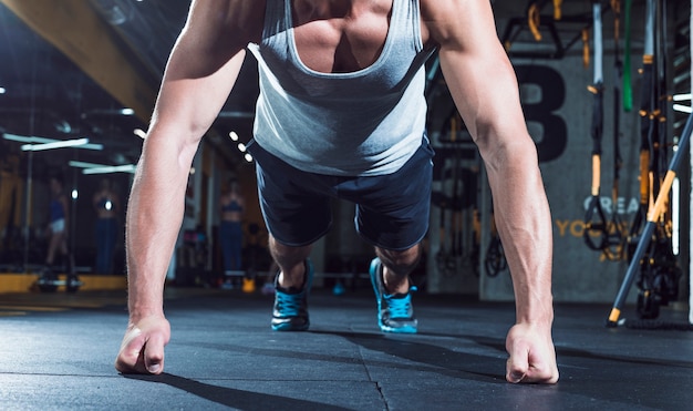 Foto close-up da mão de um homem musculoso fazendo push ups no ginásio