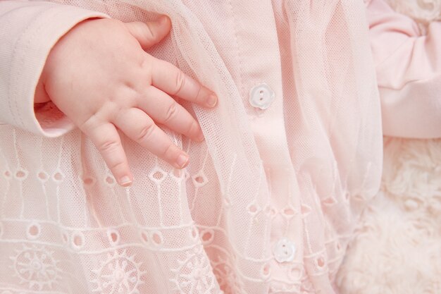 Close-up da mão de uma menina recém-nascida em um vestido rosa com rendas e bordados. cartão postal é uma menina. copyspace