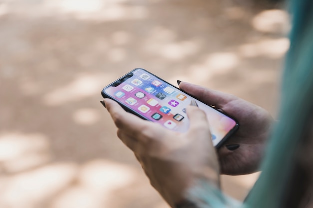 Foto close-up da mão de uma mulher segurando o telefone móvel com vários ícone de aplicativo na tela