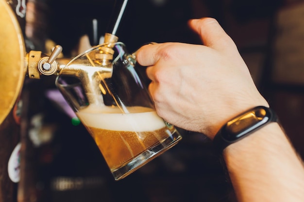 Foto close-up da mão do barman na torneira de cerveja derramando uma cerveja lager