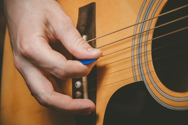 Close-up da mão do guitarrista tocando violão