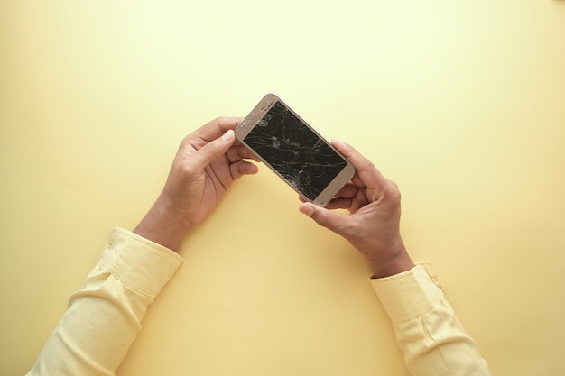 Close-up da mão do homem segurando o telefone inteligente quebrado