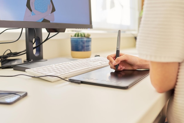 Close-up da mão do jovem desenho no computador usando a mesa digitalizadora. Educação, freelancer, estudar na escola e faculdade, hobbies e lazer, tecnologia na criatividade