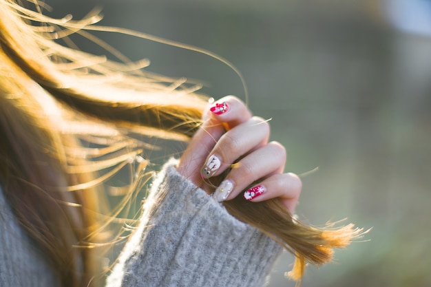 Close-up da mulher com unhas pintadas, tocando seu cabelo