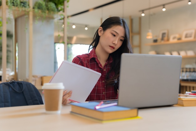 Foto close-up da mulher de negócios jovem sentado segurando o notebook na mão na mesa e assistindo notebook