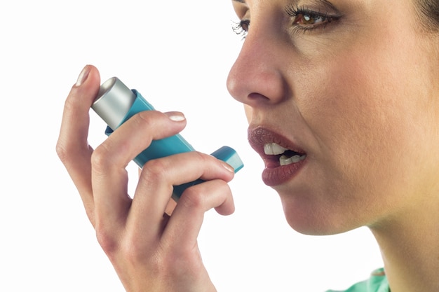 Foto close-up da mulher desviando o olhar enquanto usa inalador de asma