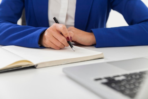 Close-up da mulher em blazer azul está fazendo anotações em uma mesa