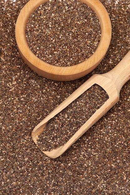Close up da tigela e da colher de madeira de sementes orgânicas naturais de chia