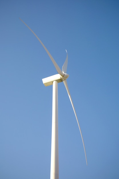 Close up da turbina do moinho de vento e lâminas gerando eletricidade sobre um céu azul. Conceito de produção de energia limpa e ecológica.