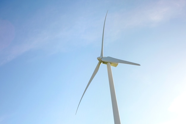 Close up da turbina do moinho de vento e lâminas gerando eletricidade sobre um céu azul. Conceito de produção de energia limpa e ecológica.