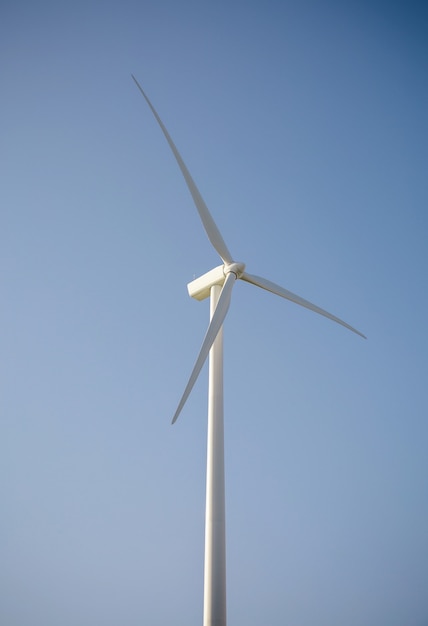 Foto close up da turbina do moinho de vento e lâminas gerando eletricidade sobre um fundo de céu azul. conceito de produção de energia limpa e ecológica.