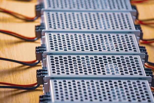 Close up das caixas de malha de metal da fonte de alimentação e fios estão em uma mesa de madeira na produção de computadores de alta tecnologia. Conceito de alta tecnologia e informática