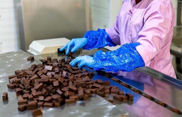 Close-up das mãos da trabalhadora classifica a linha de produção de doces de chocolate na fábrica