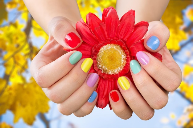 Foto close-up das mãos de uma mulher com verniz para unhas em flor