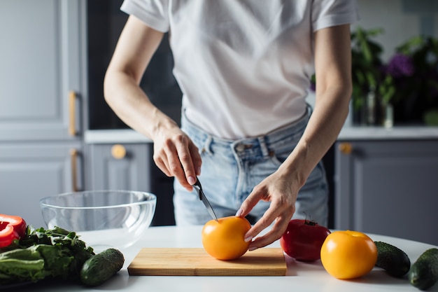 Close-up das mãos de uma mulher que corta vegetais para salada