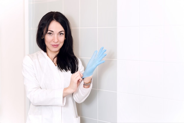 Foto close-up das mãos do médico feminino calçar luvas cirúrgicas esterilizadas azuis na clínica médica