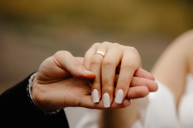 close-up das mãos dos noivos com alianças de casamento