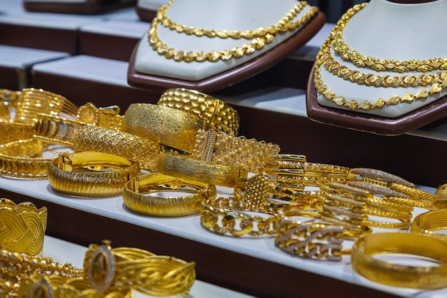 Close-up das pulseiras de anéis de colares de ouro de joias exibidas no fundo da vitrine da vitrine da loja de varejo de beleza