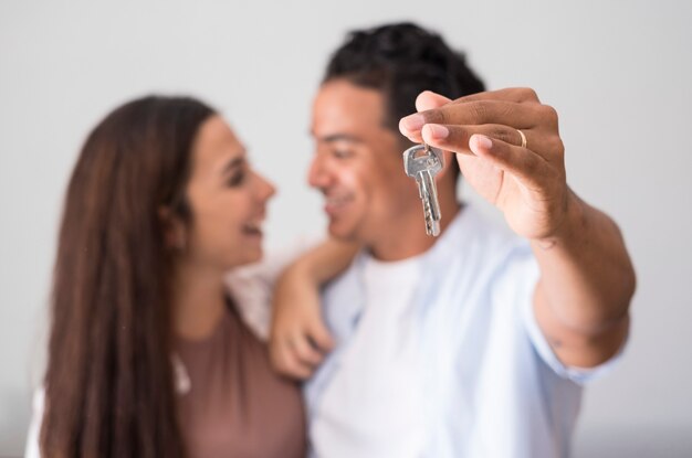 Close up das teclas de casa mostradas por um jovem casal interracial feliz no conceito de plano de fundo