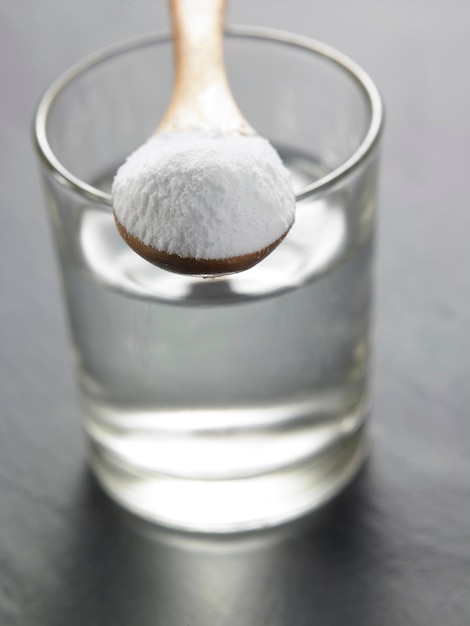 Foto close-up de açúcar em pó com água em copo de bebida sobre a mesa