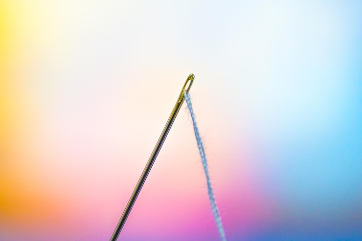 Foto close-up de agulha e fio contra um fundo colorido