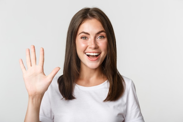 Close-up de alegre mulher jovem e atraente sorrindo, mostrando cinco dedos, brancos.