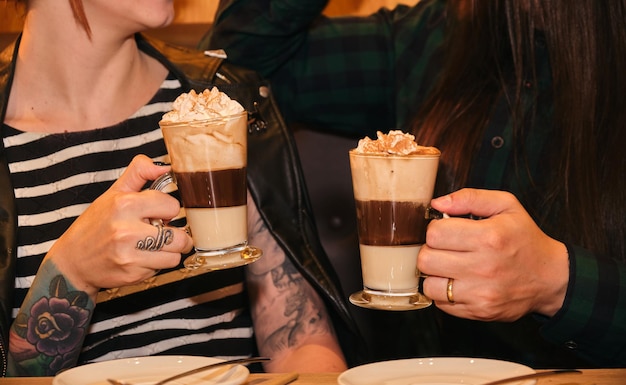 Close-up de alguns amigos tatuados tomando um café cremoso Saindo do conceito