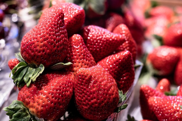 Foto close-up de alguns morangos suculentos, frescos e apetitosos em caixas transparentes ideais para preparar uma deliciosa salada de frutas de baixa caloria, mas com todo o sabor