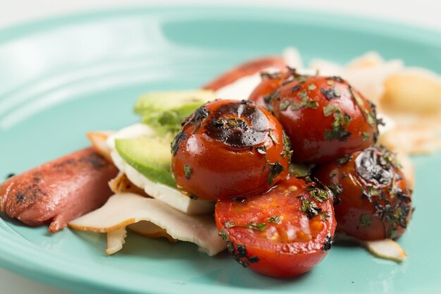 Foto close-up de almoço com tomates salsicha e abacate em prato na mesa