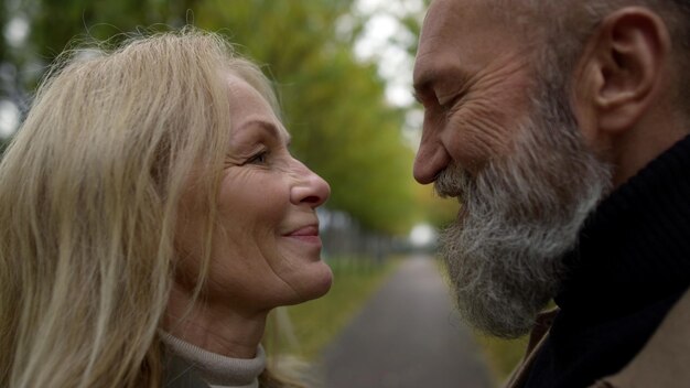 Close-up de amantes felizes se abraçando em um lugar romântico Side shot de um belo casal caucasiano olhando um para o outro ao ar livre Família idosa afetuosa e alegre se apaixonando
