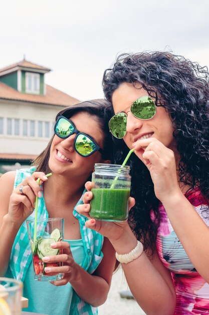 Foto close-up de amigos com óculos de sol tomando um smoothie em um restaurante