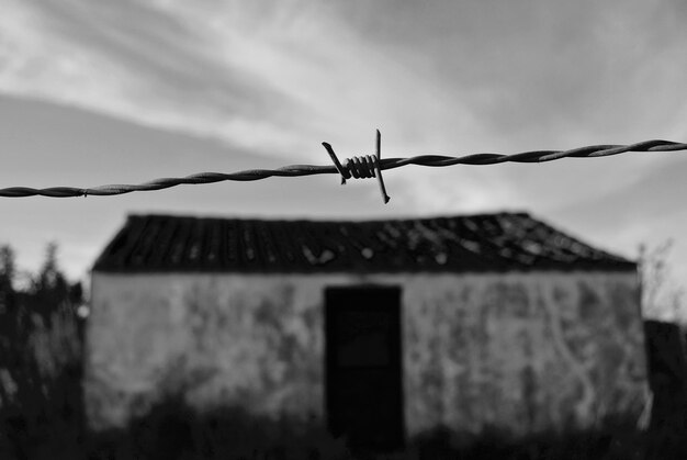 Foto close-up de arame farpado contra a estrutura construída