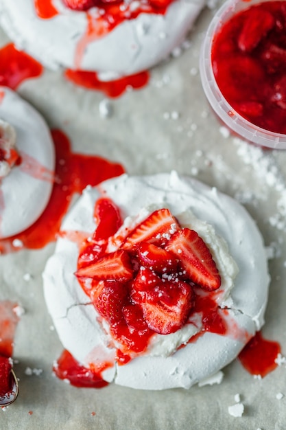 Foto close up de baiser merengue branco caseiro com morango e geléia.