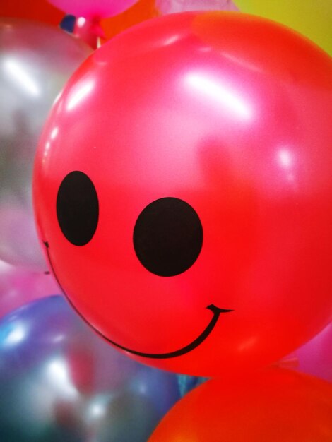 Foto close-up de balão vermelho com rosto sorridente antropomórfico