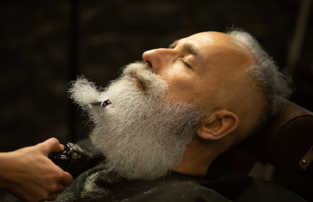 Close-up de barba de corte de barbeiro para o homem na barbearia.