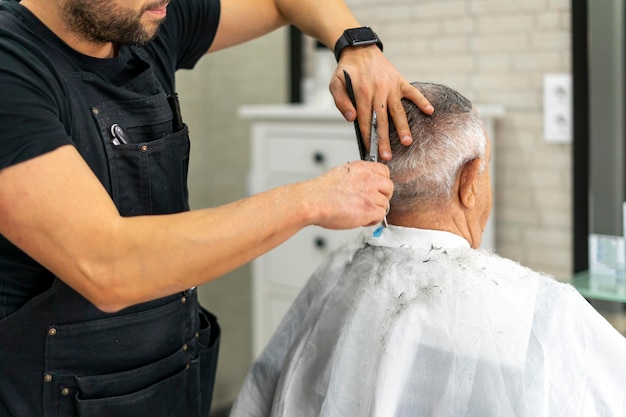 Close-up de barbeiro cortando o cabelo de um velho com uma tesoura