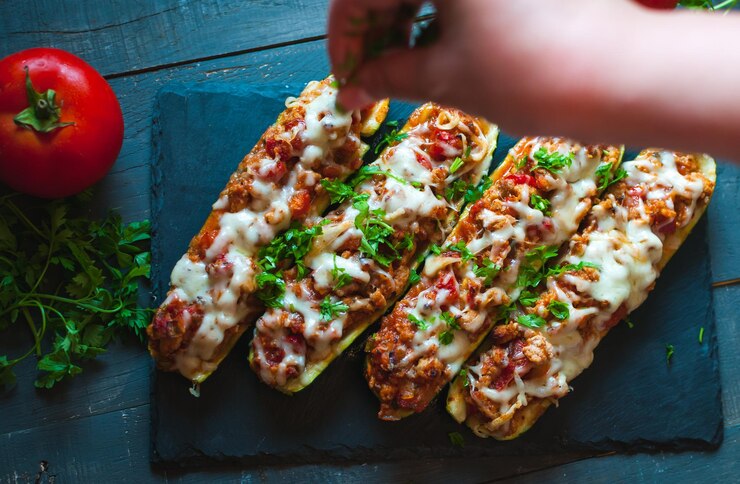 Foto close-up de barcos de abobrinha recheados com carne moída, molho de tomate picante, queijo e salsa fresca