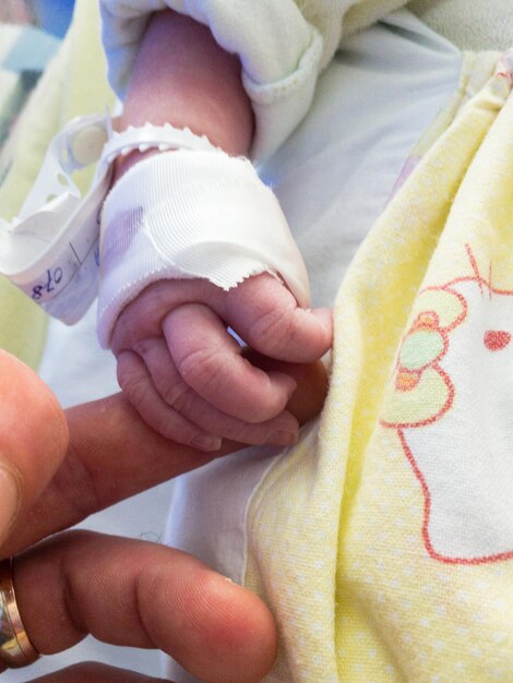 Foto close-up de bebê e homem de mãos dadas