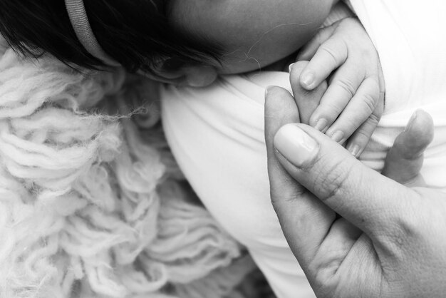 Close-up de bebês mão pequena cabeça ouvido e palma da mãe macro preto e branco foto de bebê recém-nascido após o nascimento segurando firmemente o dedo dos pais conceito de família e casa pediatria de saúde